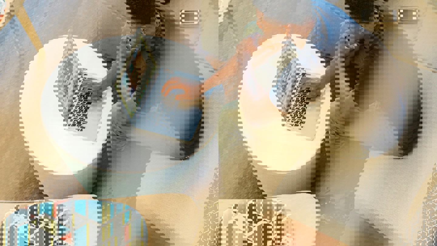 A shot through a 2nd floor interior window of a man on his laptop