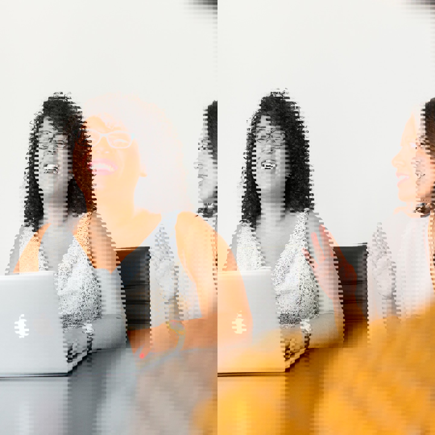 Young woman on her laptop laughing with colleagues